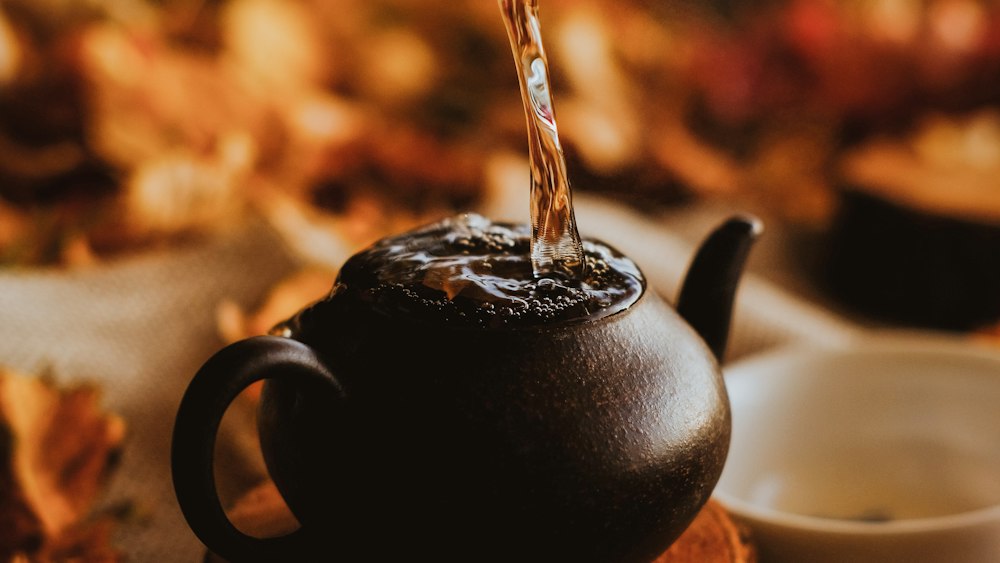 Aromatic Tea Pouring from Black Ceramic Teapot into White Ceramic Teacup