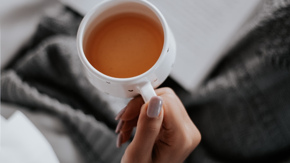 Comparing Caffeine Kick: Person with White Ceramic Mug in Tea Section