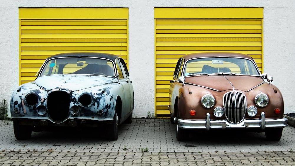 Comparison of Retro Cars in Front of Yellow Garage