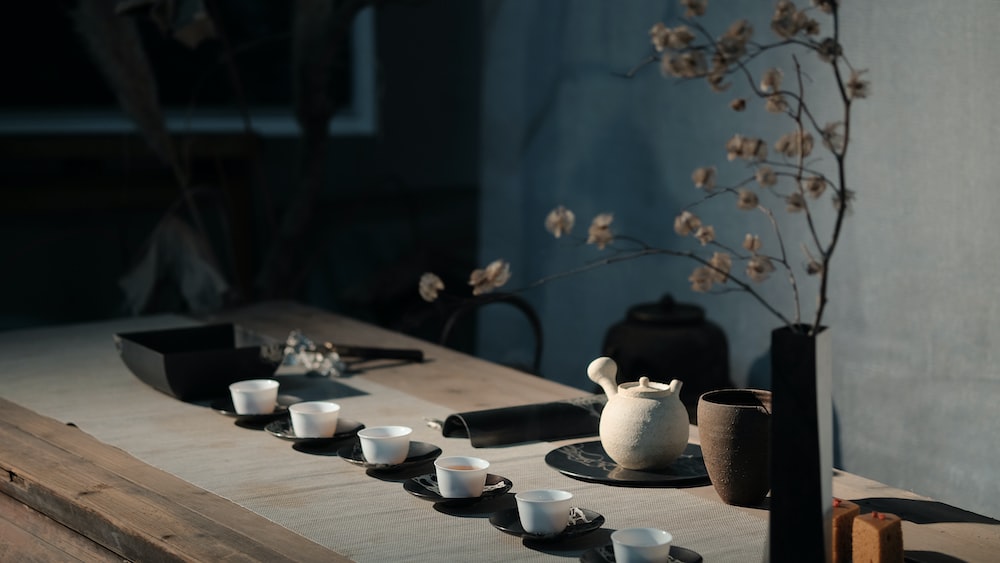 Fermented Tea Ceremony with White Flowers in a Black Ceramic Vase
