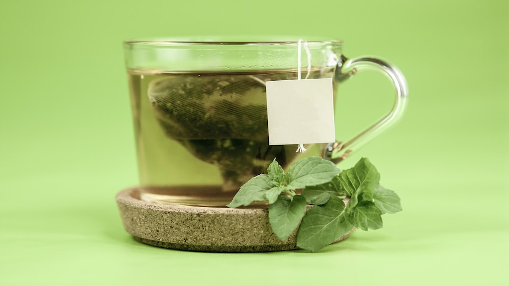 Green Tea in a Clear Glass Mug with Green Leaves