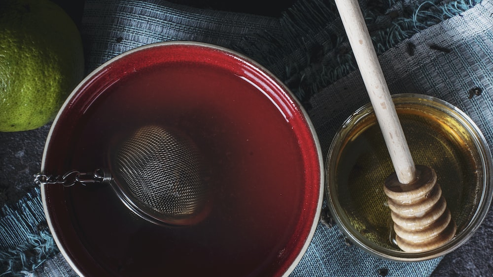 Herbal Tea Delight: A Refreshing Infusion in a Red Ceramic Bowl