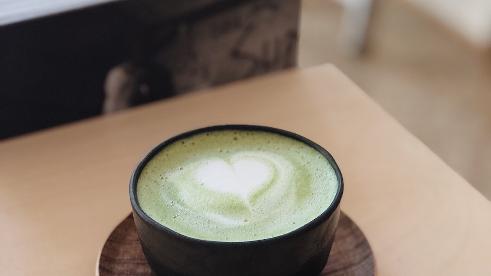Matcha Latte in a Black Ceramic Cup with Brown Saucer