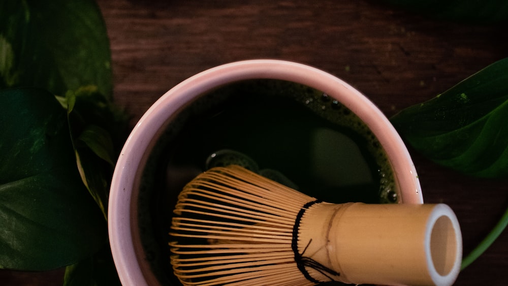 Morning Matcha Delight: A Brown Wooden Brush on a White Ceramic Mug
