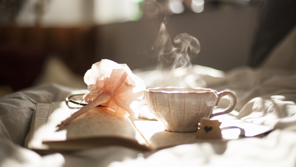 Mugwort Tea: Ceramic Teacup on Book with Pink Flower Decor