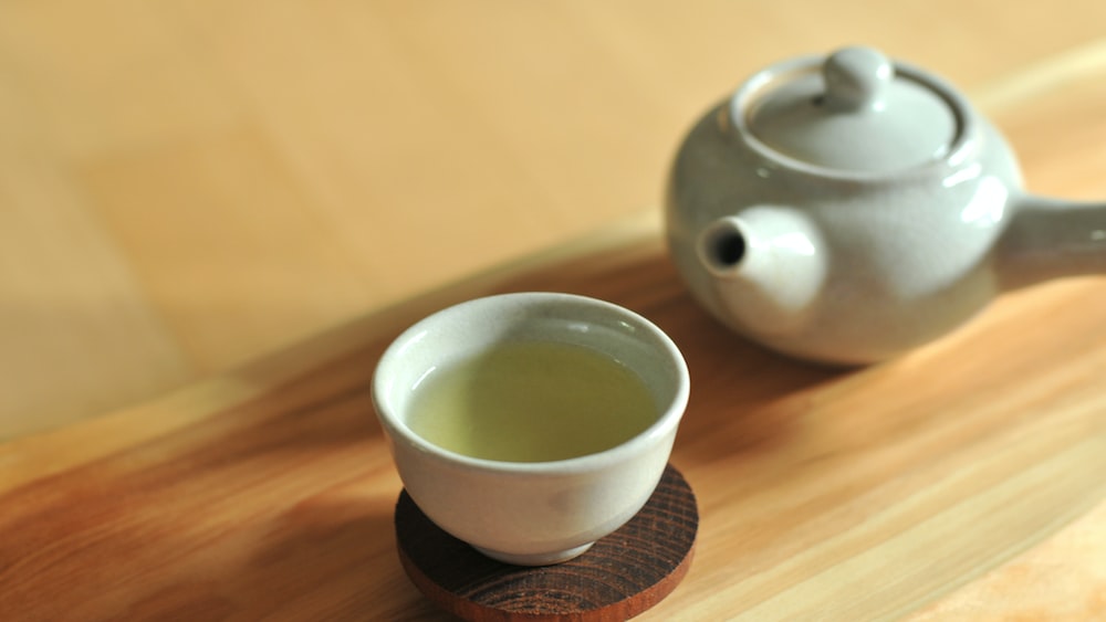 Pu Erh Tea: White Ceramic Teacup on Brown Wooden Table