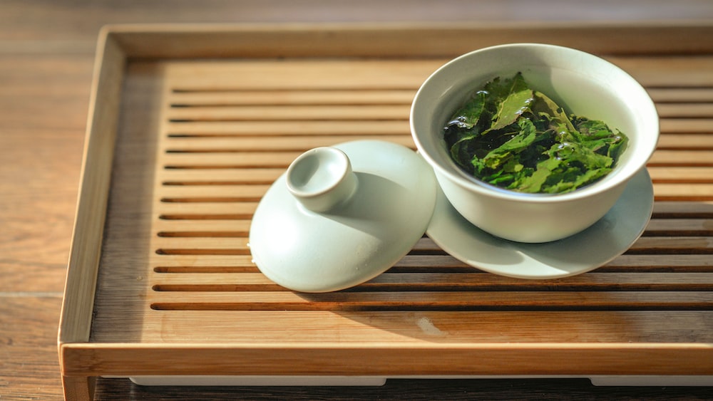 Tea Leaves in a White Ceramic Bowl with Open Lid