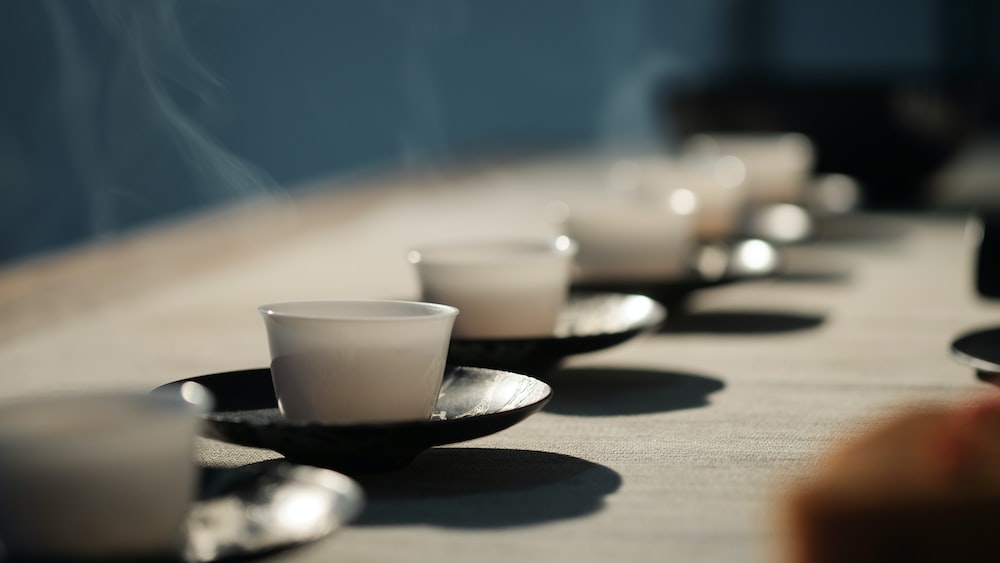 Tea ceremony with white disposable cups on black saucers