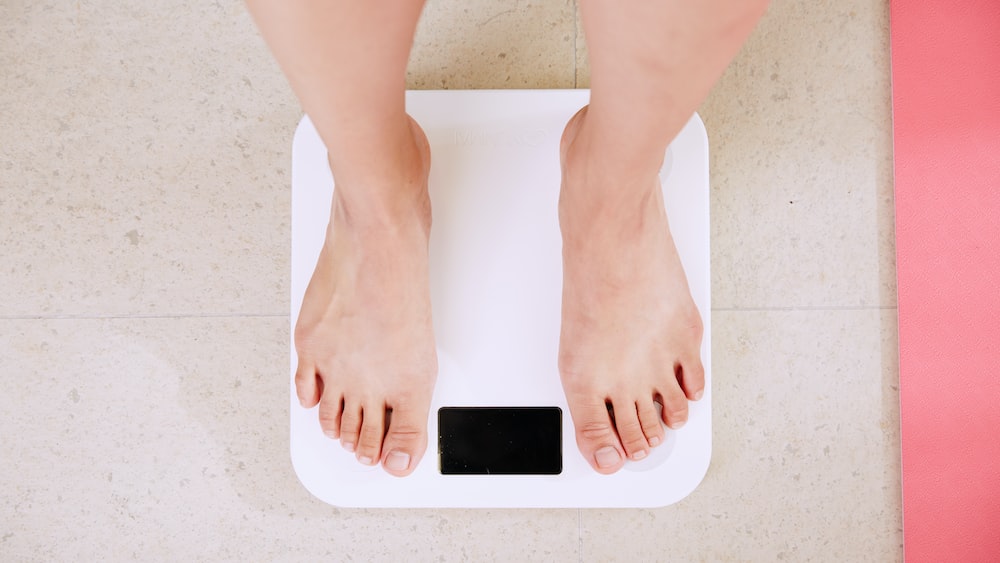 Weight Loss Illustrated: Person Standing on a White Digital Bathroom Scale